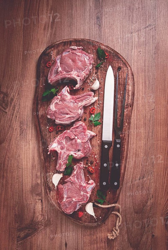 Raw calf meat, meat on the bone, meat for barbecue, cutting board, with spices and herbs, top view