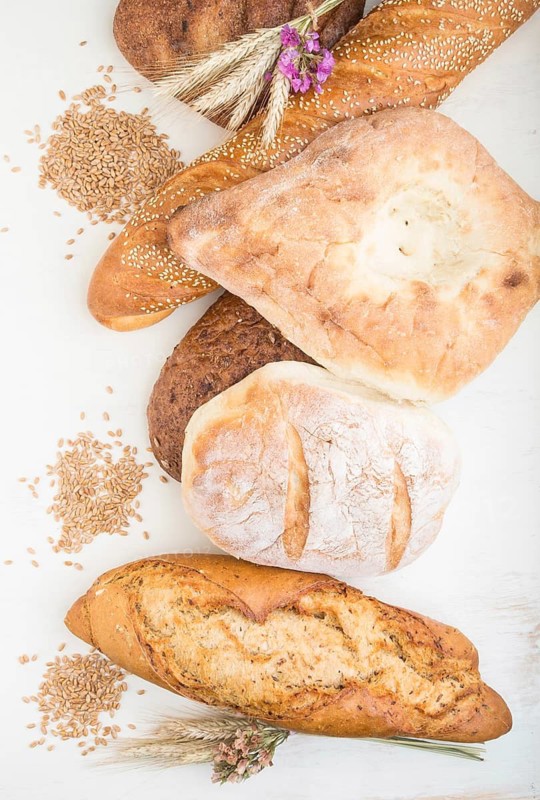 Different kinds of fresh baked bread on a white wooden background. top view, flat lay, close up