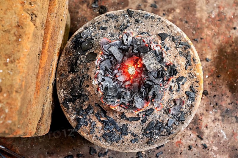 Close-up of a fire pit with glowing charcoal and glowing red center on a metal plate, A kiln for sapphires in the city of Ratnapura in Sri Lanka
