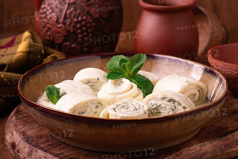 Gebjalia, a traditional Georgian dish, cold appetizer of cheese with mint, Megrelian cuisine, on a wooden table, homemade. no people