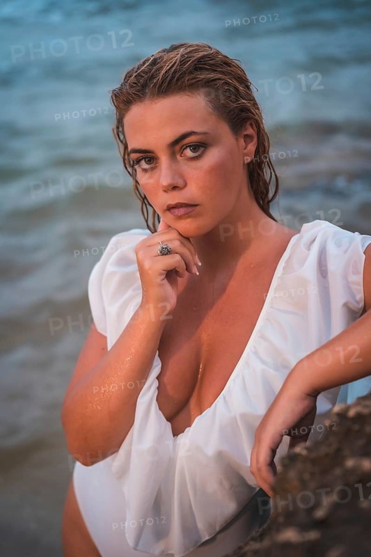Lifestyle of a blonde Caucasian girl in a white swimsuit. Smiling after getting out of the water, vertical photo