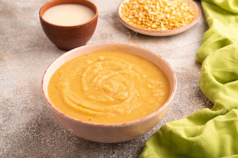 Pea cream soup, Puree, porridge in ceramic bowl on brown concrete background and green linen textile. Diet, healthy eating concept. side view, close up, minimalism