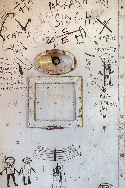 Graffiti on old steel jail cell door with spyhole and service-hatch at the prison museum at Merksplas near Hoogstraten, Flanders, Belgium