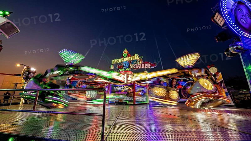 Lively funfair with fast-turning, illuminated carousel at night, carousel and the hustle and bustle of summer profit in Eisenach