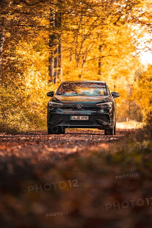 Car on an autumn path in the forest, immersed in golden leaves and sunlight, electric car VW ID5, Gechingen, Black Forest, Germany