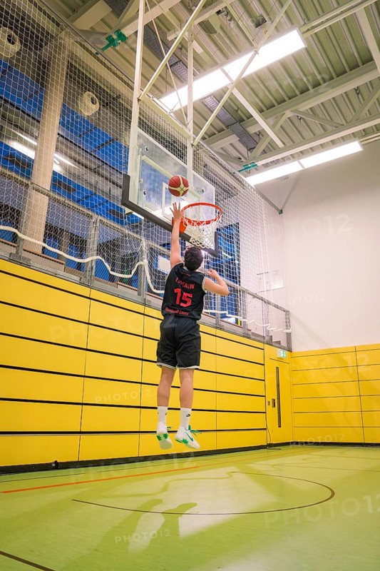 A player jumps up for a dunk in a yellow gym, basketball TSV Calw, Germany