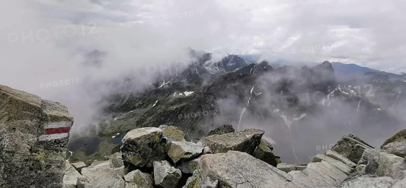 Mountains covered in fog with rugged rocks under cloudy sky, hiking trail, High Tatras, Slovakia