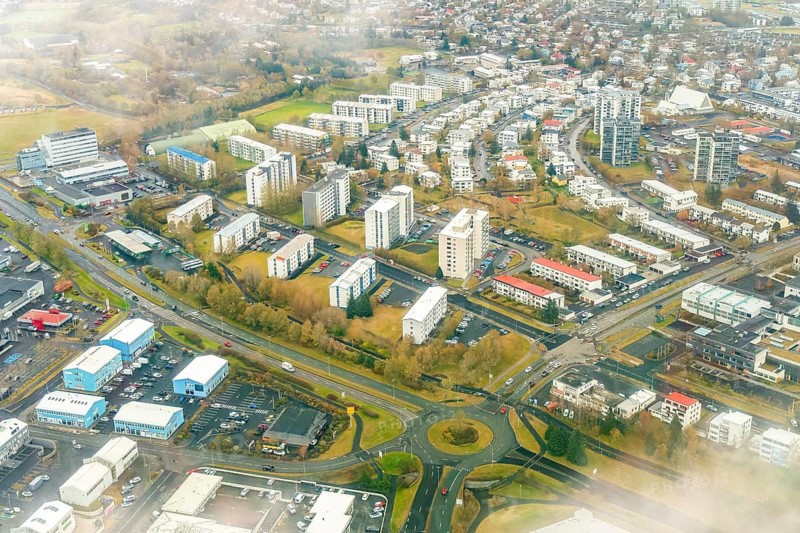 Captivating aerial shot capturing a vast suburban area of Reykjavik, Iceland, showcasing residential buildings, roads, and green spaces intertwined in an urban setting