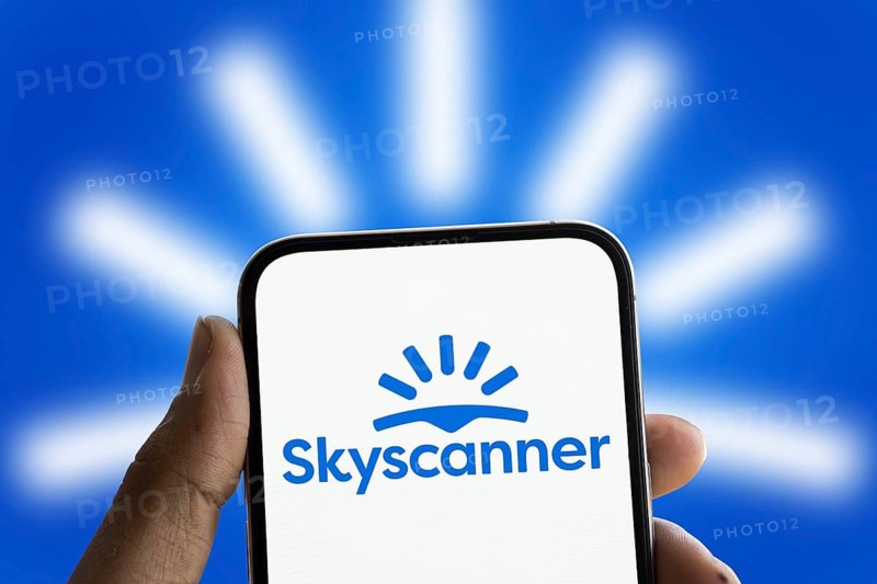 Skyscanner logo is displayed on smartphone. Skyscanner Ltd. is a search aggregator and travel agency