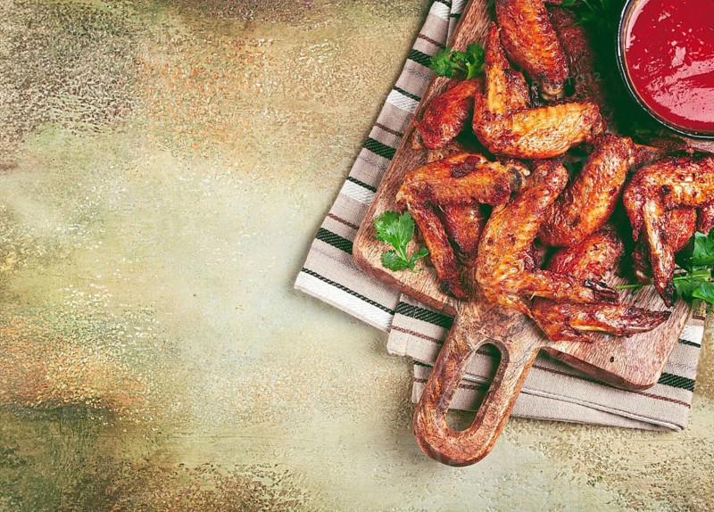 Fried in the oven, chicken wings, with spices, tomato sauce, on a cutting board, gray background, no people, homemade