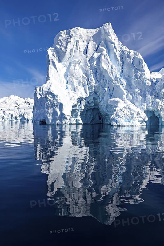 Large iceberg with impressive height reflected in the calm water, icebergs in the Southern Ocean in Antarctica