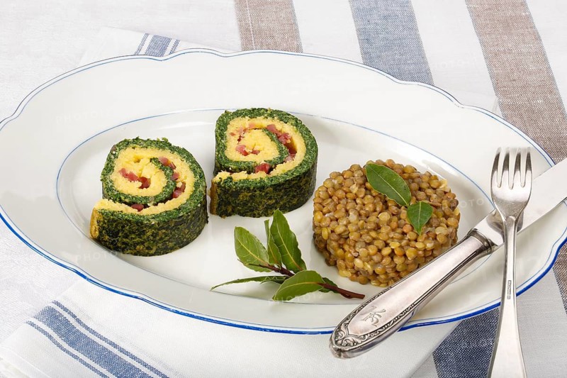Southern German cuisine, polenta spinach roulade with alblentils served on serving platter, bay leaves, lentil vegetables, smoked meat, bacon cubes, healthy, food photography, studio, Germany