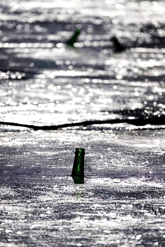 Discarded glass bottle in a frozen lake, winter, Germany
