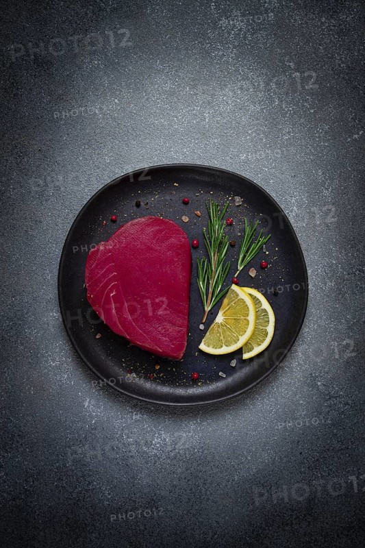Fresh red tuna fillet, for steak, raw, top view, on a black plate, no people