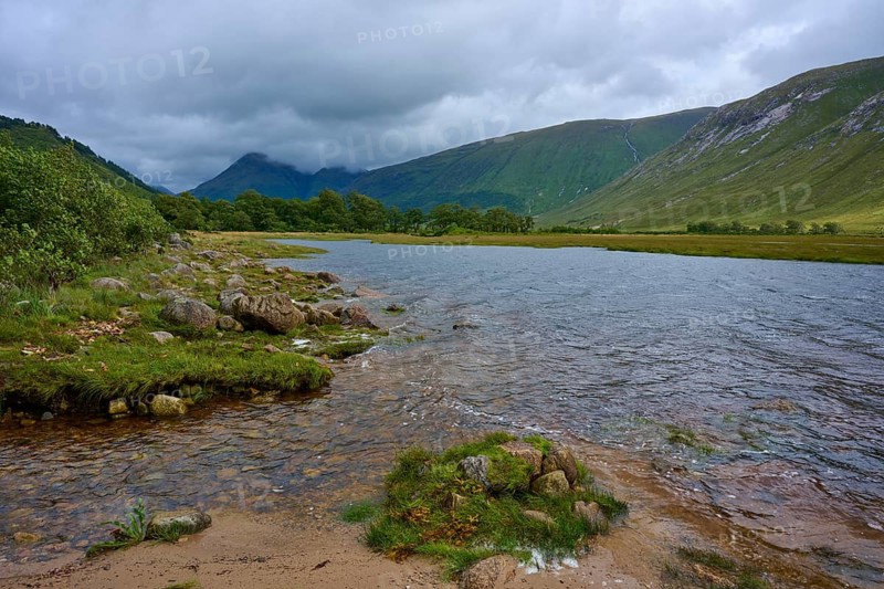 A river flows through a green landscape under a cloudy sky, Loch Etive, Argyll and Bute, Scotland, United Kingdom, Great Britain