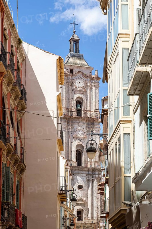 Narrow alley with a view of an old church tower under a clear sky, Malaga, Spain