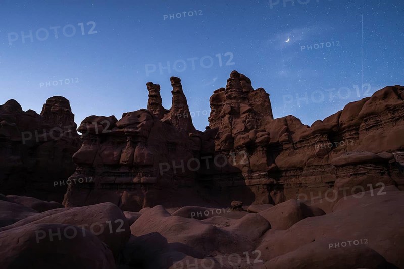 A majestic view of Goblin Valley State Park under a starry sky in Utah, showcasing the unique rock formations with a crescent moon