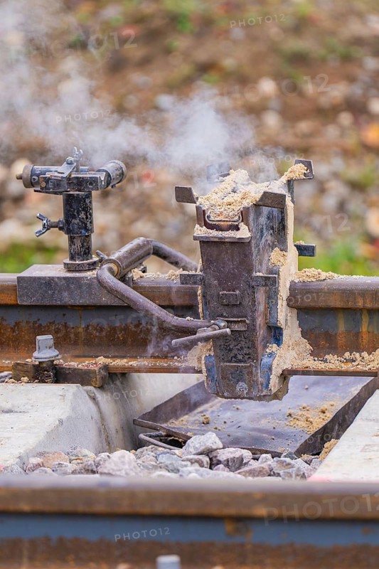 Detailed view of a metal device on the tracks with smoke development, rail welding, track construction Hermann Hessebahn, Calw, Black Forest, Germany
