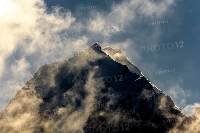 Stunning autumn beauty of Mount Cook in New Zealand. The mountain peak is enveloped in dramatic clouds, capturing the serene and awe inspiring landscape