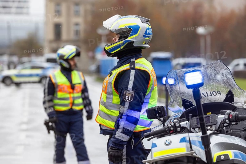 Police officers are standing in the rain. Police motorcycles with flashing lights in front of the Federal Chancellery. Berlin, Germany