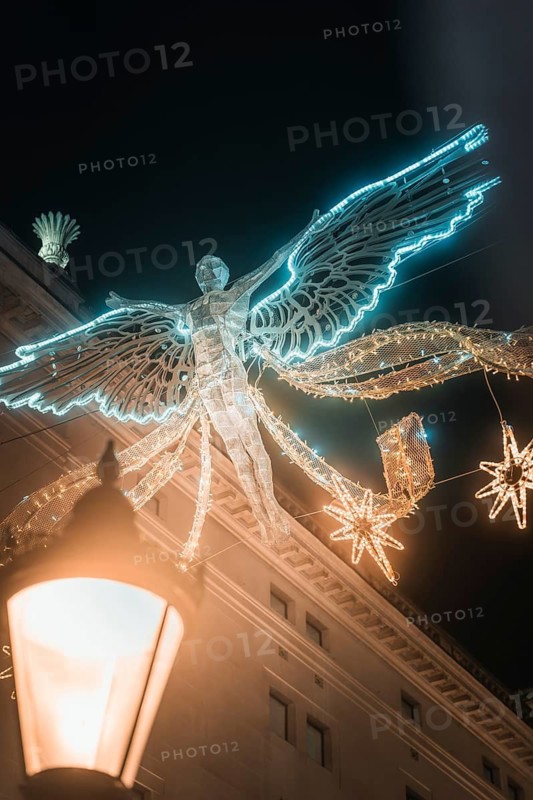 Illuminated angel figure floating over city building at night, New Year's Eve London, Great Britain