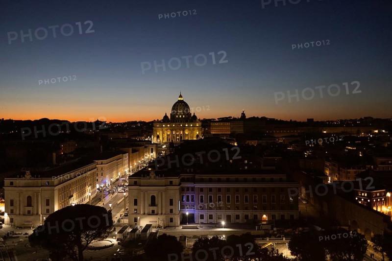 Captivating evening view of Rome's skyline, highlighting the Vatican Dome illuminated against the early night sky Streets below shimmer with lights, adding a magical ambiance