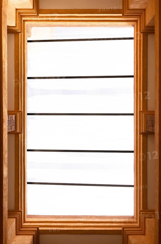 High-angle view of a rectangular skylight with a warm-toned concrete frame and white glass. The window is structured with parallel lines, offering a minimalist design element