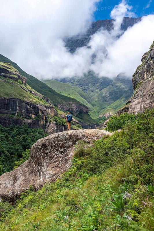 Female hiker standing in front of landscape with mountains and fog, Drakensberg National Park, KwaZulu Natal, South Africa