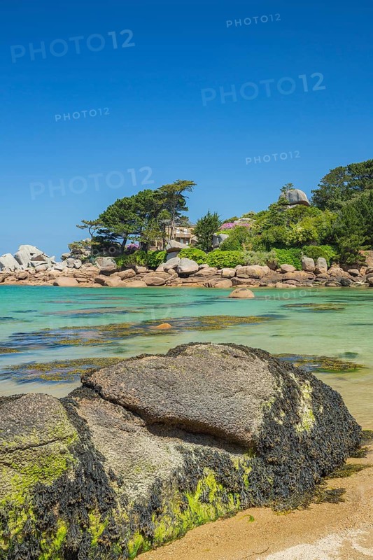 Beach with rocks and sand at the Plage Saint Guirec, with clear blue sky and colors as in the carribians