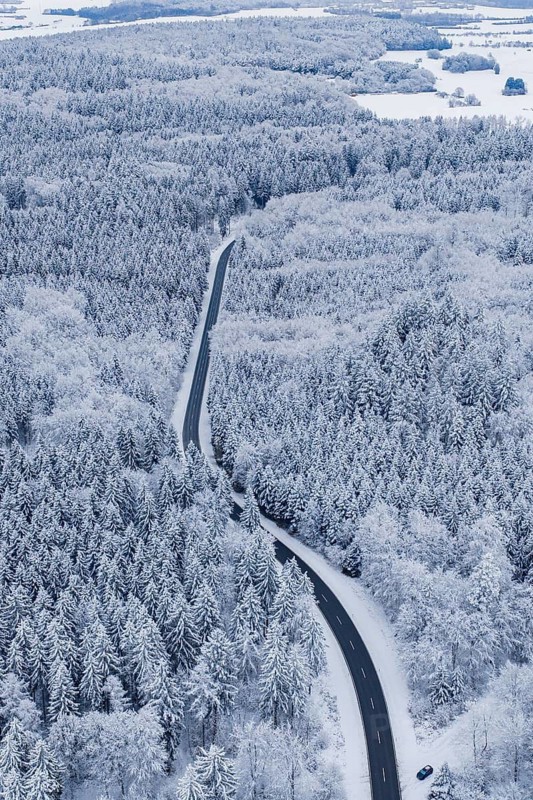 Snowy road snakes through a thick winter forest, Gechingen, Calw district, Germany
