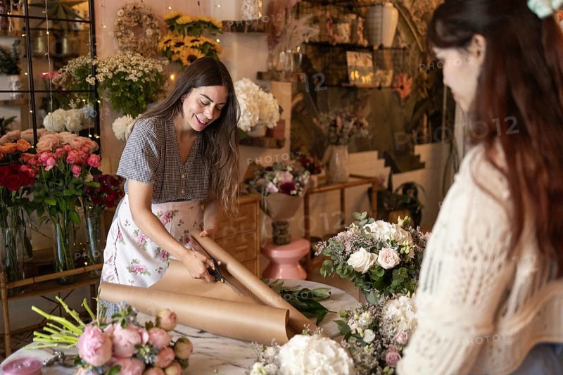 Woman actively engage in creating beautiful floral arrangements in a vibrant florist shop. Surrounded by a variety of colorful flowers, she focus on their craft with precision