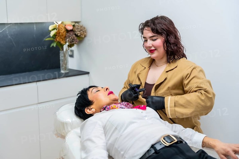 Specialist in black gloves performing a non invasive cosmetic treatment on a female patient's face, enhancing beauty and providing skincare in a modern aesthetic clinic setting