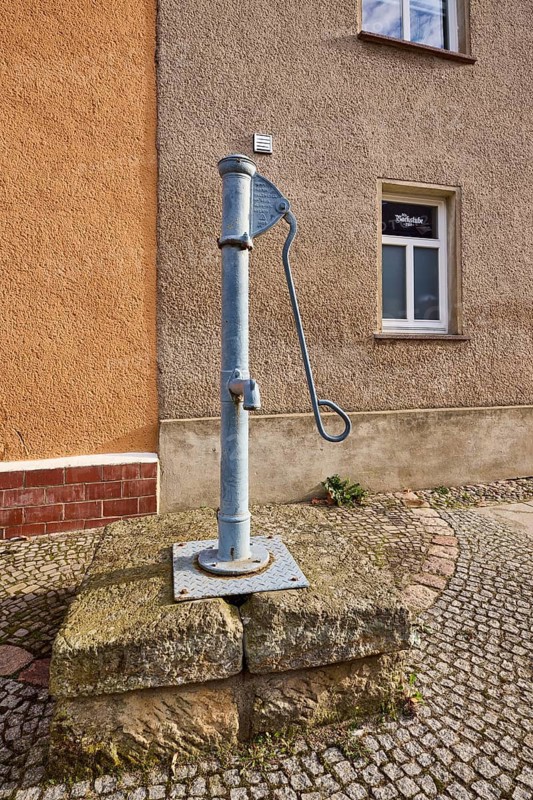 Historic pump, hand pump, pavement, cobblestones, facade with windows, Mühlberg Elbe, Elbe-Elster district, Brandenburg, Germany