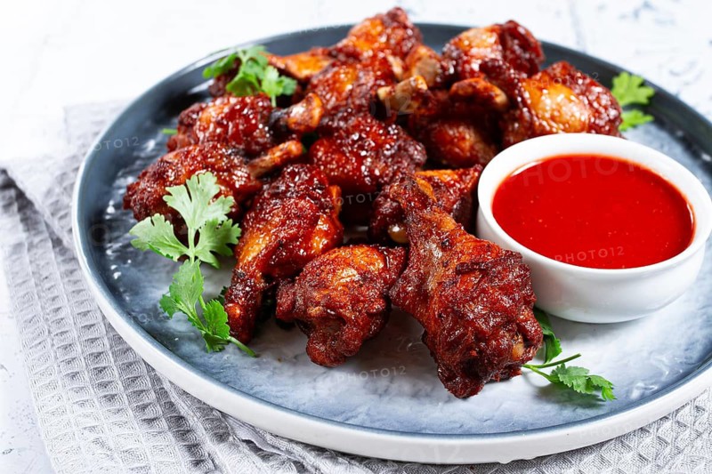 Crispy pieces of fried chicken, on a plate with sauce and herbs, in a modern kitchen environment, there are no people