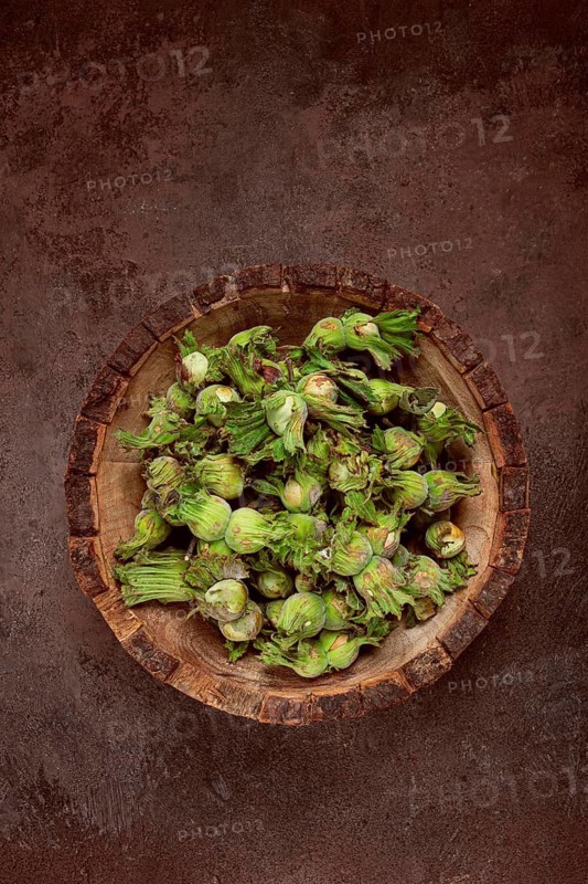 Fresh, green hazelnuts, close-up, in a wooden bowl, unpeeled, top view, no people