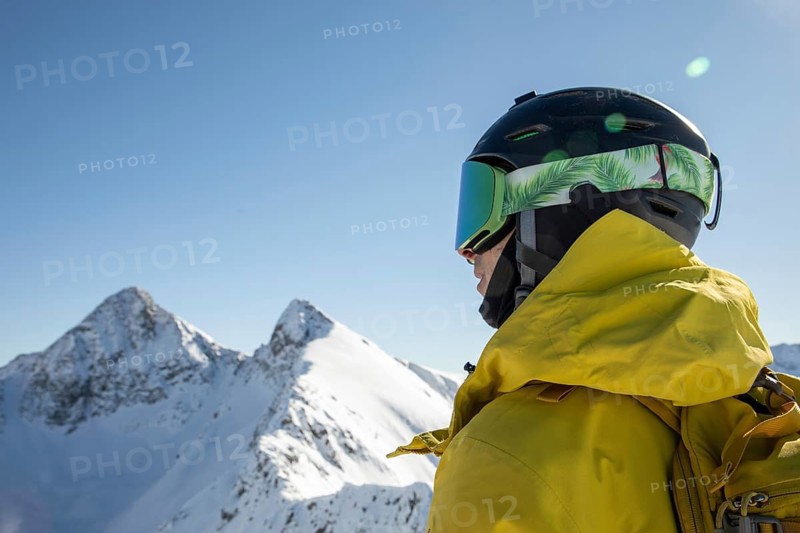 Skier in a yellow jacket and helmet, looking at pristine snow-covered peaks under a clear blue sky Captures the thrill of alpine adventure and winter sports freedom