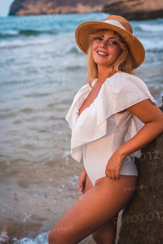Lifestyle of a blonde Caucasian girl in a white swimsuit by the sea enjoying the summer