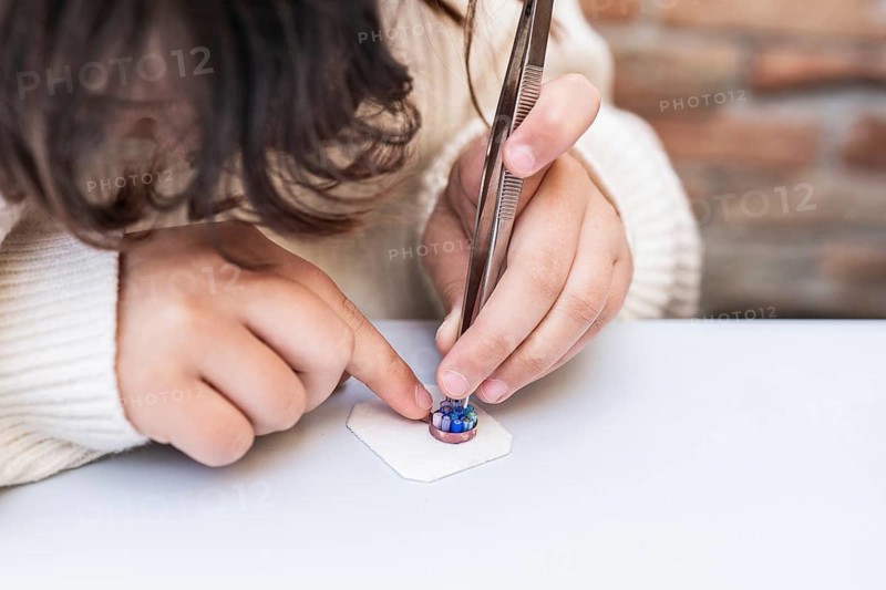 A skilled artisan precisely crafts intricate Burano and Murano glass jewelry in Venice. Delicate hands use fine tools, capturing the essence of Italian craftsmanship and tradition