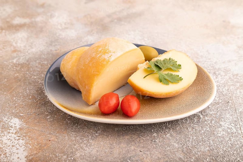 Smoked Mozzarella cheese, with tomatoes and olives on brown concrete background, side view, close up