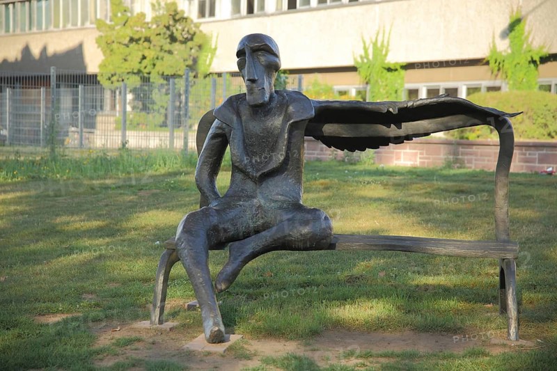 Transformation sculpture by Victor Gulchenko 2014, modern art, bronze sculpture, black figure with wing sitting on bench, mythical creature, fantasy creature, Höchst, Frankfurt am Main, Hesse, Germany