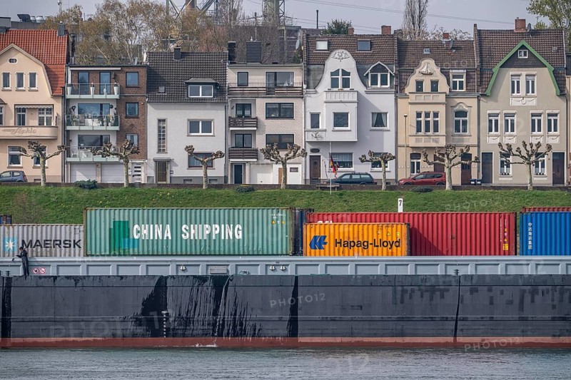 Container cargo ship on the Rhine, near Duisburg Homberg, residential buildings on Wilhelmallee, North Rhine-Westphalia, Germany