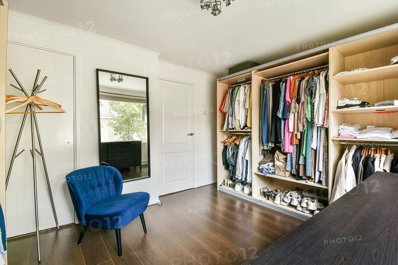 A well-organized modern wardrobe showcasing a variety of clothing and accessories, complemented by elegant interior decor and wooden flooring