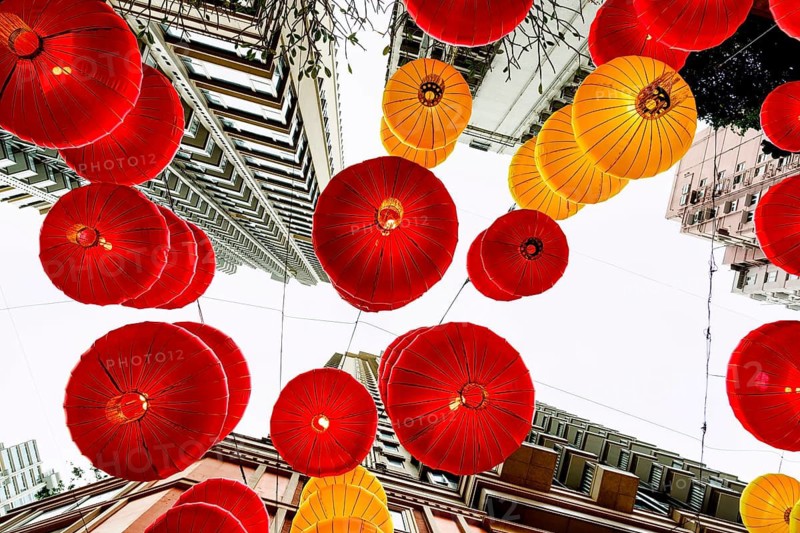 From below view of striking red and yellow lanterns adorning the cityscape of Hong Kong during the Chinese New Year celebration, capturing a festive and cultural ambiance against urban architecture