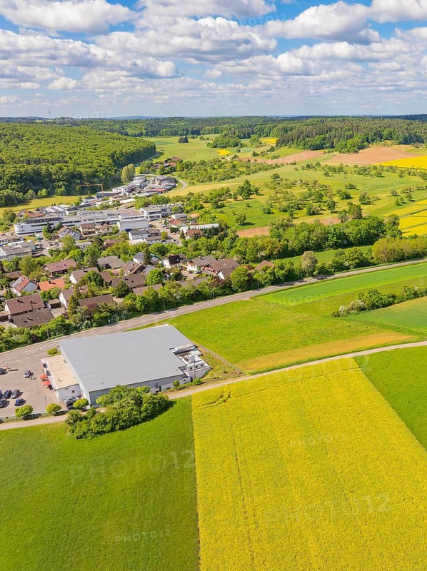 Farm village surrounded by green and yellow fields under a cloudy sky, Gechingen, Black Forest, Germany
