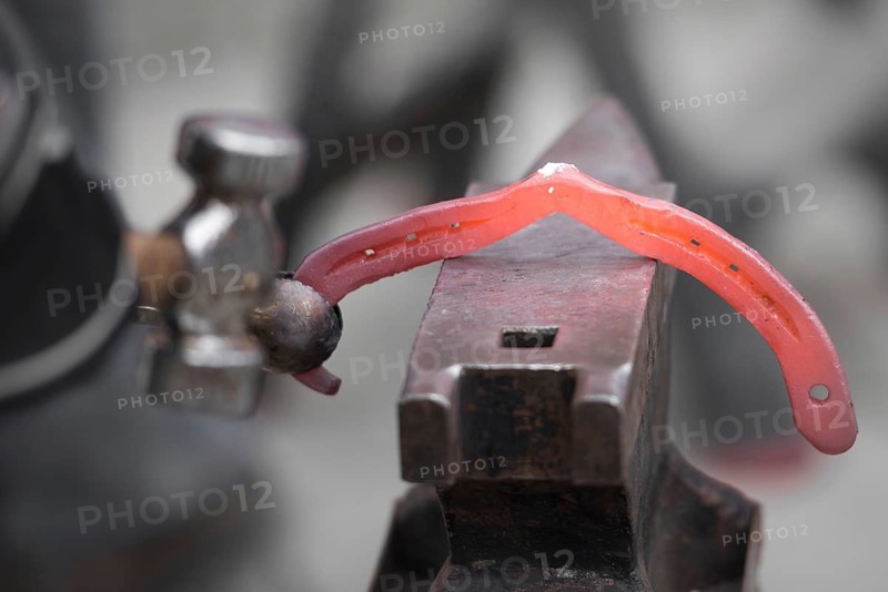 The blacksmith shakes the horseshoe on the anvil