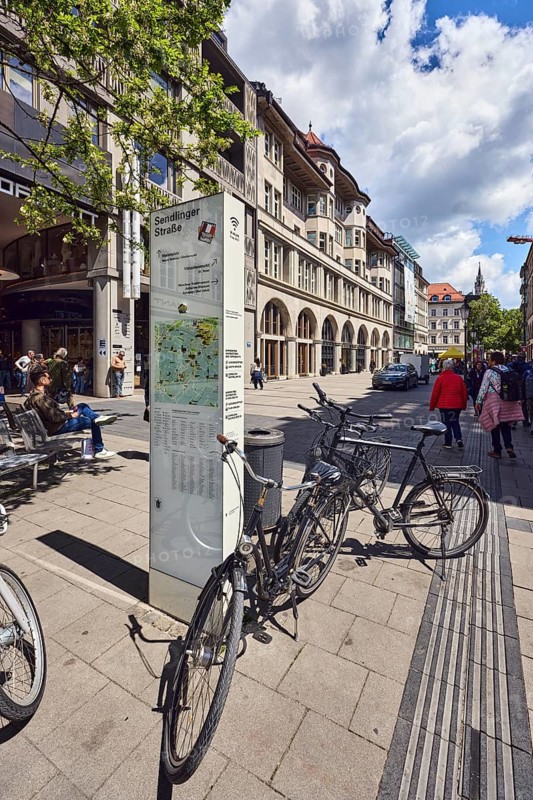 Stele with location sign, pedestrian zone, general architecture, residential buildings and commercial buildings, shops, shopping, bench, bicycles, trees, pedestrians as a secondary motif, blue sky, cumulus clouds, Sendlinger Straße, Munich, state capital, district-free city, Bavaria, Germany