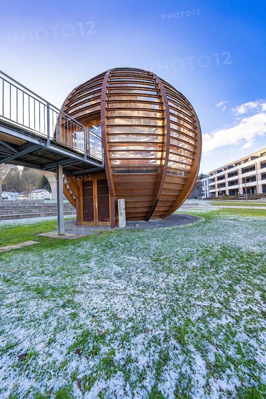 Modern wooden ball with adjoining metal bridge in front of a blue sky, surrounded by buildings and frosty lawn, forest ball from Landesgartenschau 2012, Nagold, Black Forest, Germany