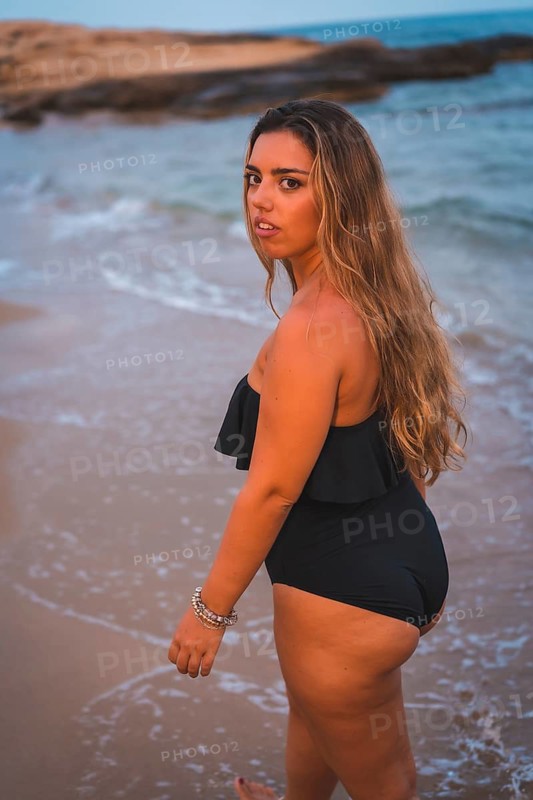 Lifestyle of a blonde Caucasian girl in a black swimsuit. Strolling on the seashore
