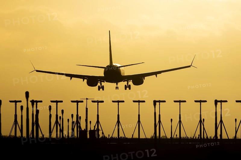 Boeing 737 commercial passenger airliner jet aircraft of Ryanair airways in flight on approach to land over runway lights at sunset at London Stansted airport, Essex, England, United Kingdom