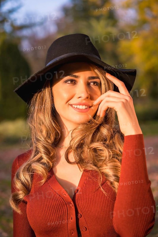 Lifestyle, portrait of a caucasian girl in a black hat at sunset in a green park